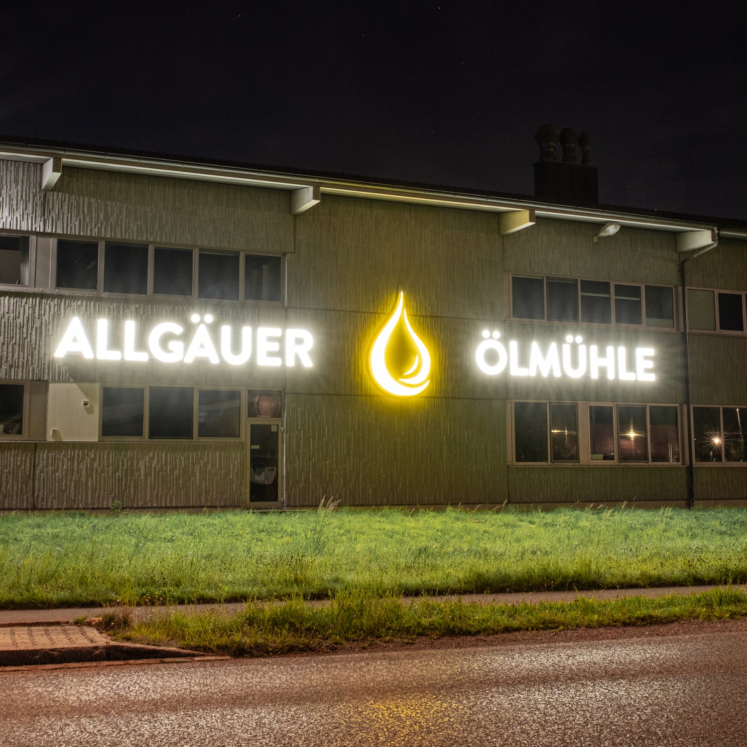 Fassade des Allgäuer Ölmühle Firmengebäudes mit Logo bei Nacht